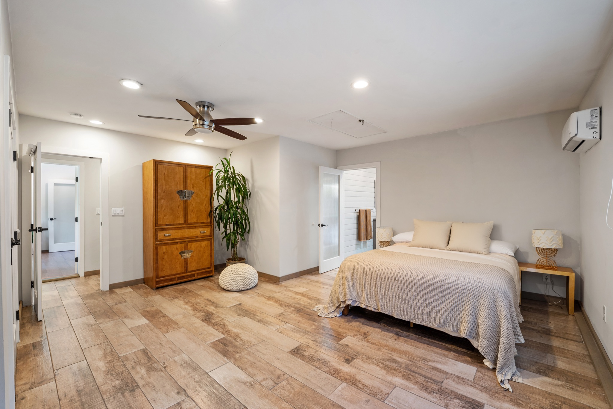 Spacious bedroom with king bed, vintage wood armoire, and ensuite bath