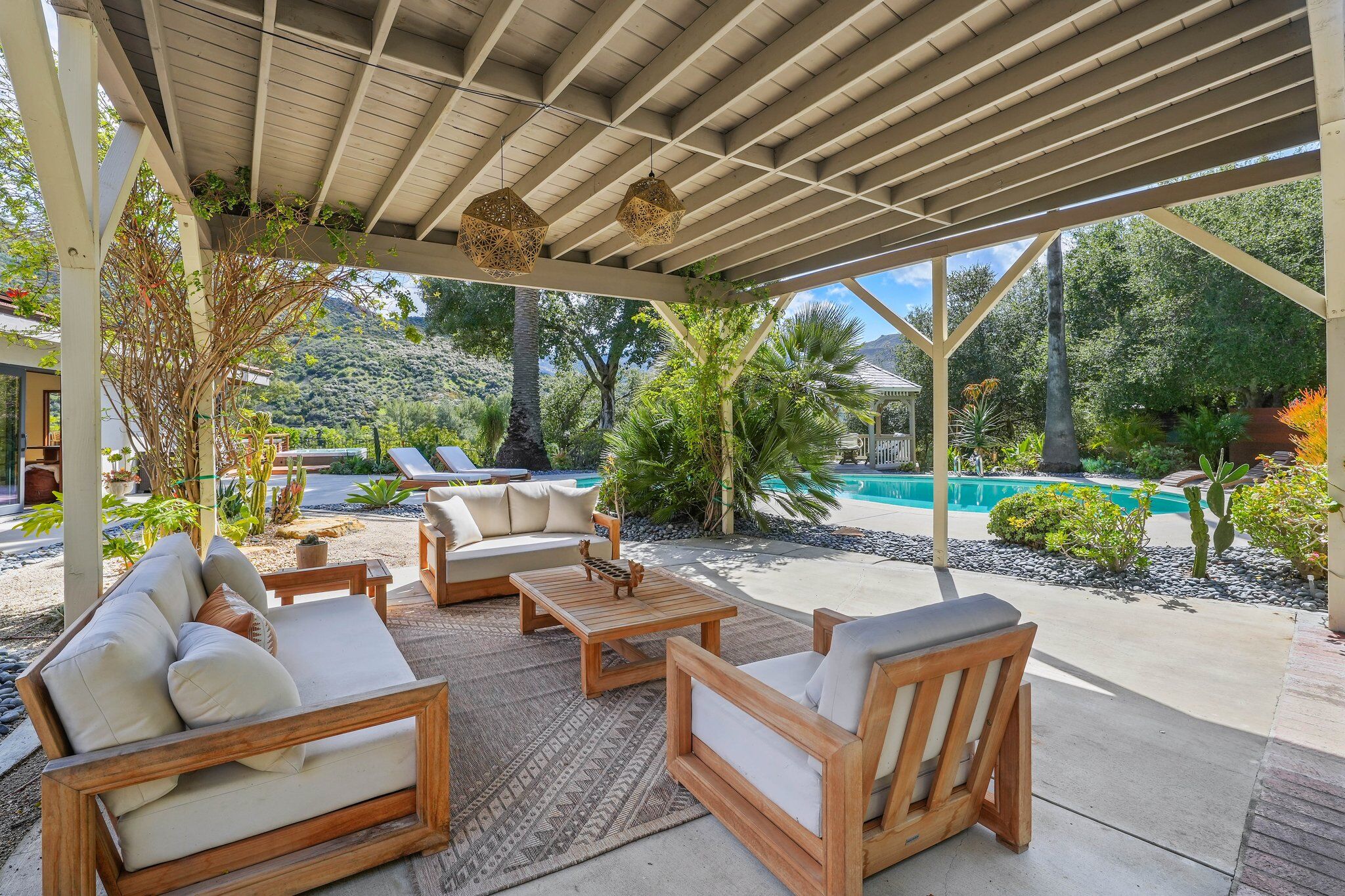 Covered patio lounge with sofas overlooking the saltwater pool