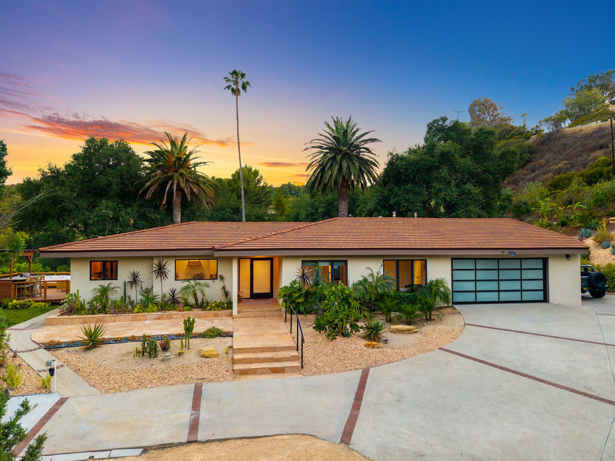Front of the ranch house at golden hour with palms rising over the driveway