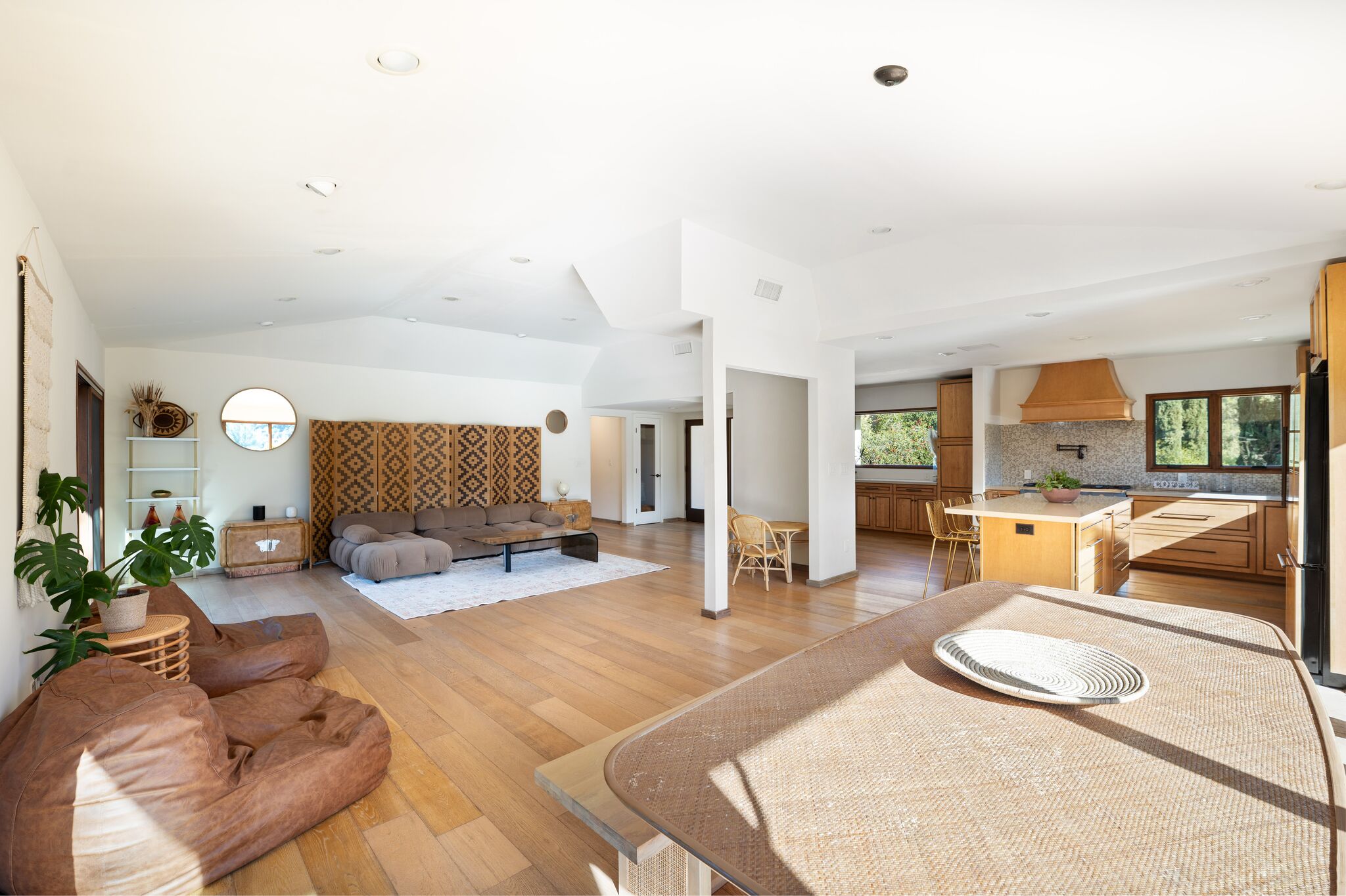 Wide view of the great room flowing past the dining table into the open kitchen
