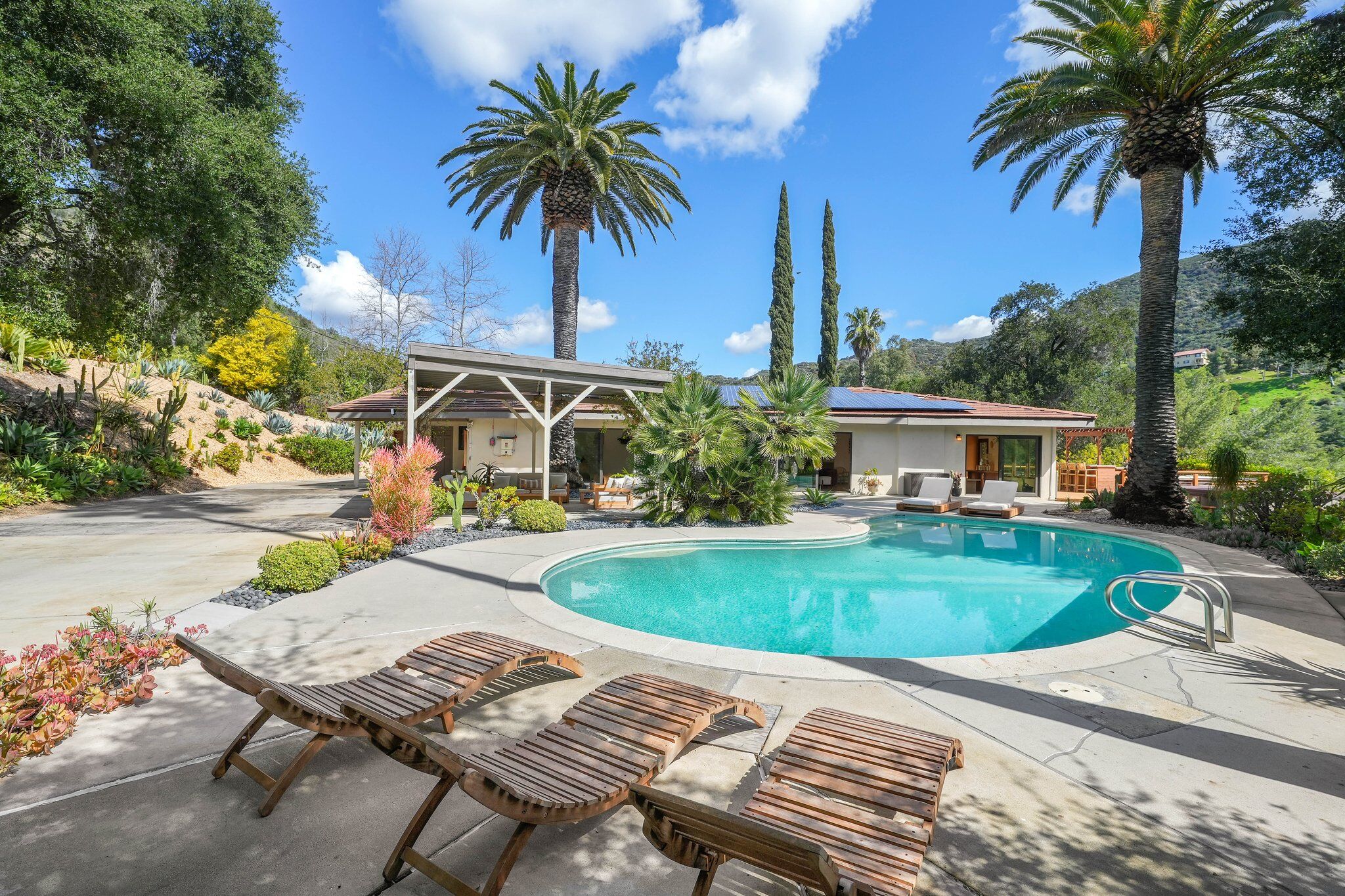Saltwater pool framed by palm trees with the ranch house beyond