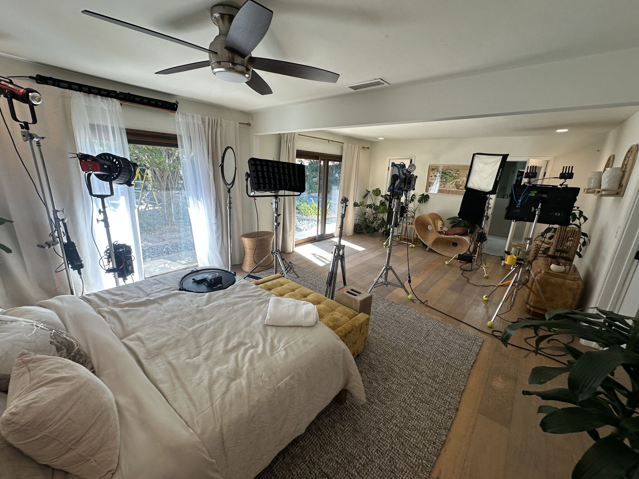Film lighting rigs and stands set up around the bed in the master bedroom during a shoot