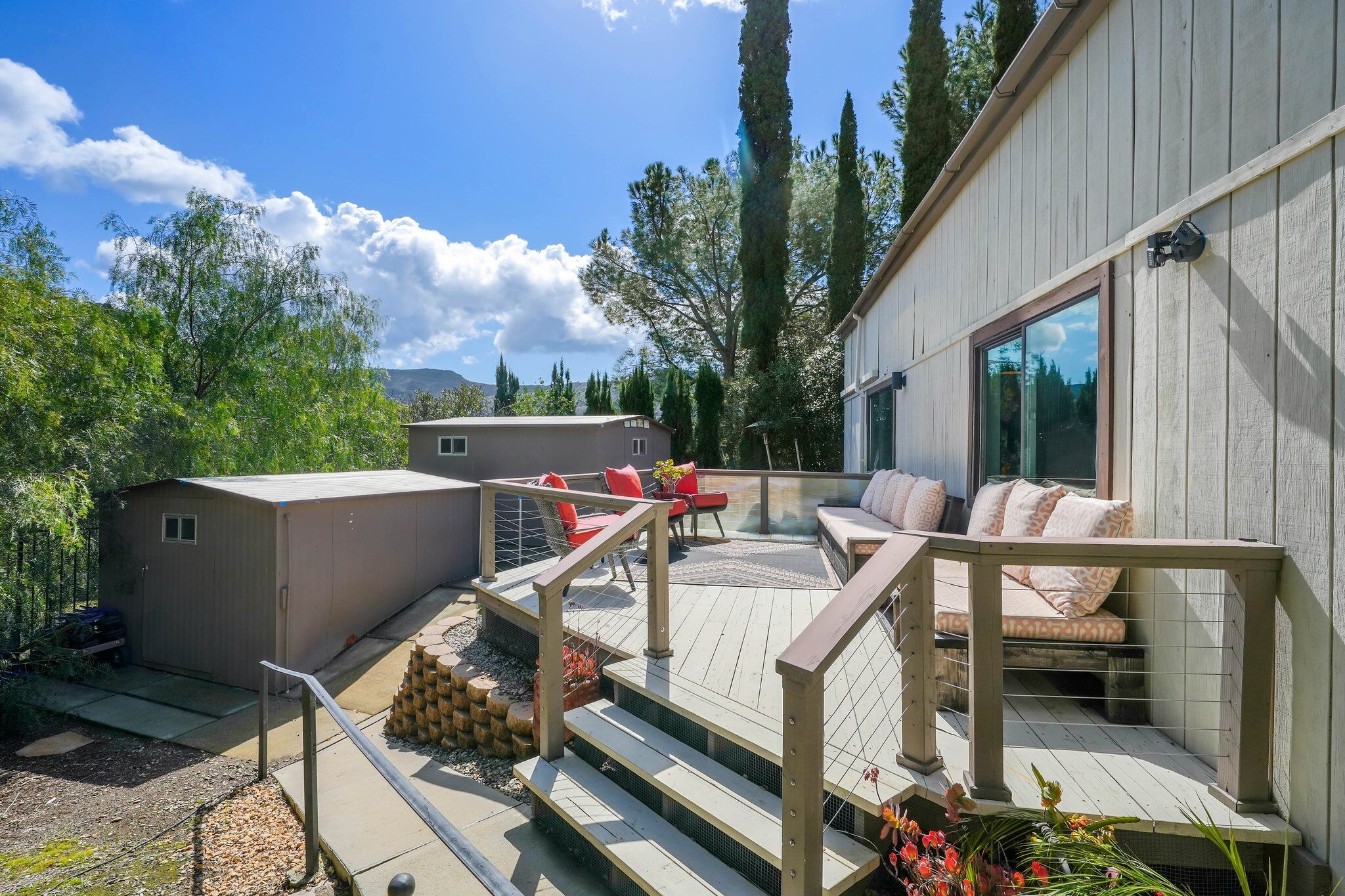 The studio exterior deck with cushioned seating, dining table, and cypress trees