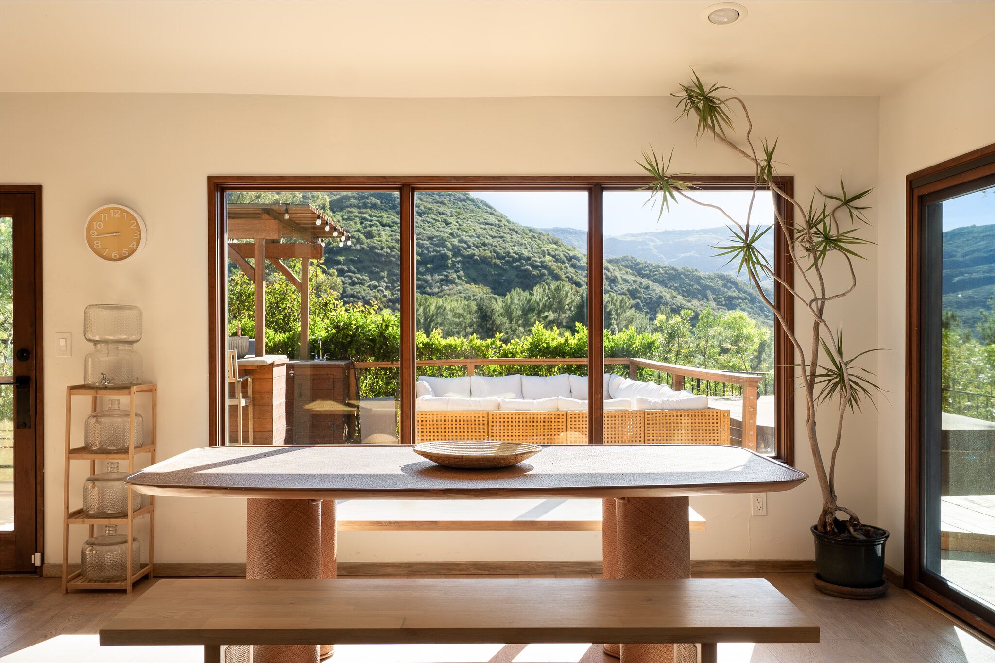 White tea room with a low woven table framed by a picture window of canyon mountains