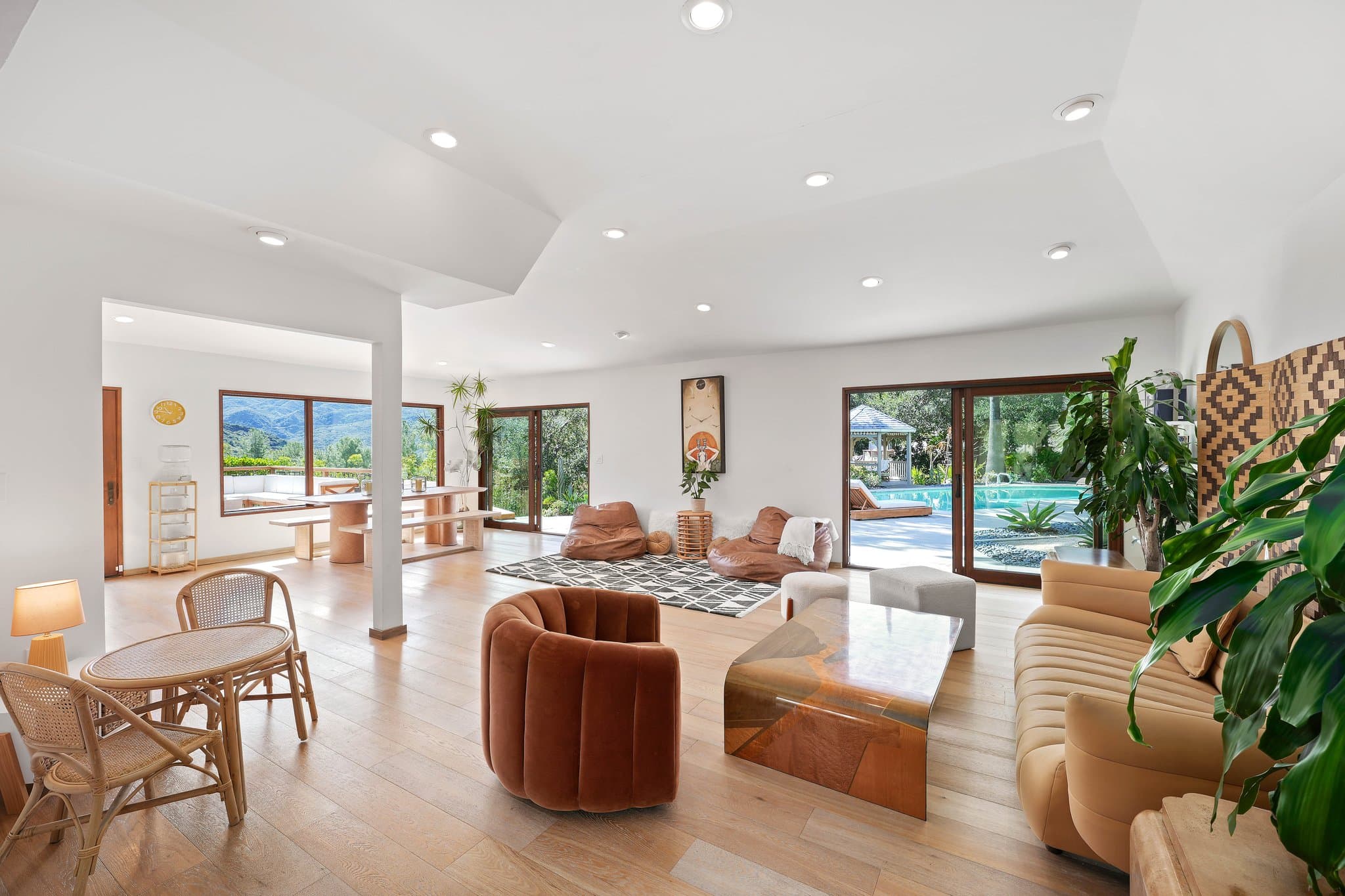 Open-concept great room with high ceilings, velvet chair, and pool views